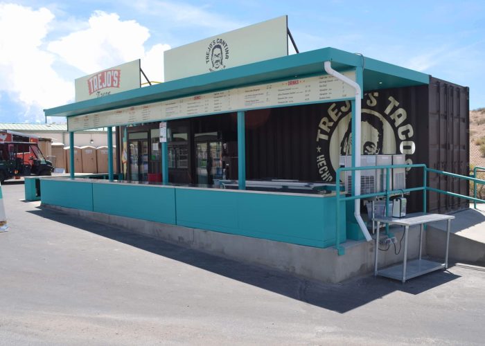 Trejo's Tacos stand with menu displays in a vibrant setting, offering diverse taco options for outdoor dining.