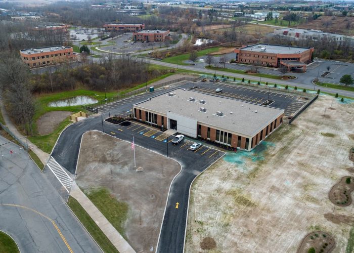 Aerial view of business complex with modern office and parking lot, set in a landscaped area.