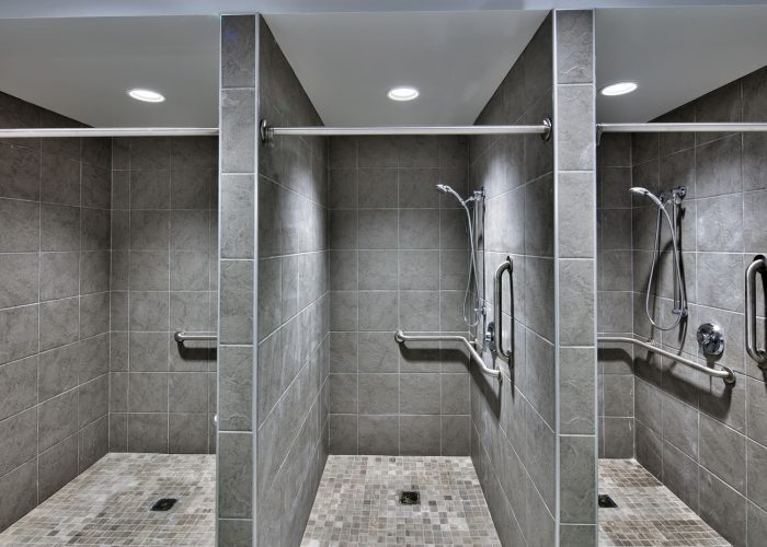 Modern accessible shower stalls with grab bars and handheld showerheads.