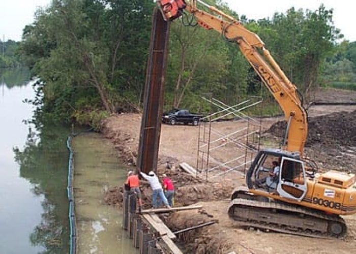 Construction crew using an excavator for riverbank reinforcement. Efficient engineering solutions by [YourCompanyName].