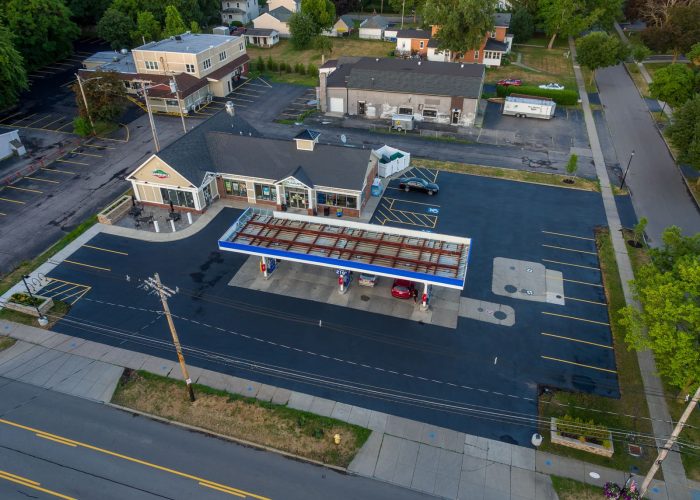 Aerial view of a convenience store with a Valero gas station, highlighting empty parking spaces and surrounding neighborhood.