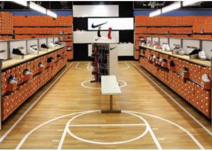 Sneaker display in a Nike store showcasing various athletic shoes on shelves with iconic branding in the background.