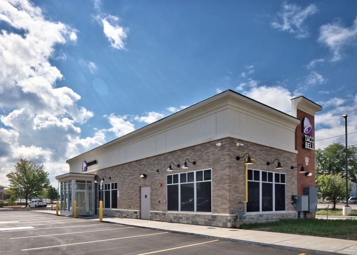 Exterior view of Taco Bell restaurant with clear skies, highlighting modern design and branding.