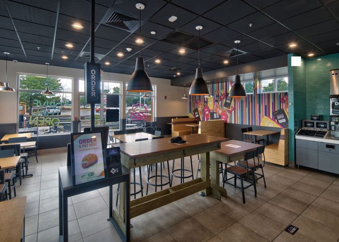 Modern fast food restaurant interior with self-order kiosk and colorful decor.