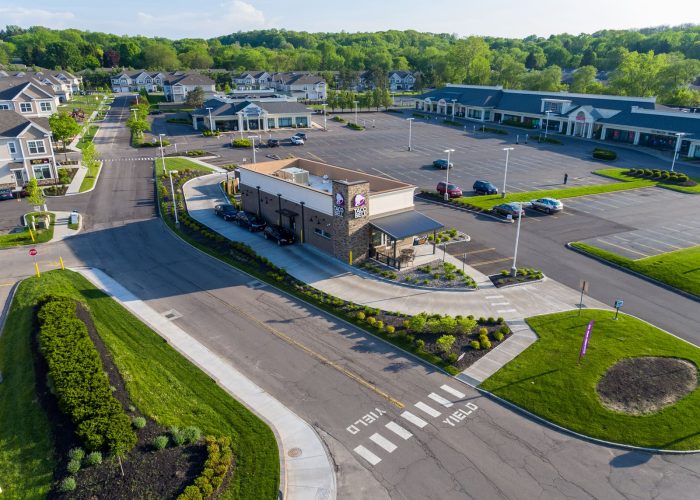 Aerial view of a Taco Bell location in a suburban shopping area with green surroundings and ample parking space.