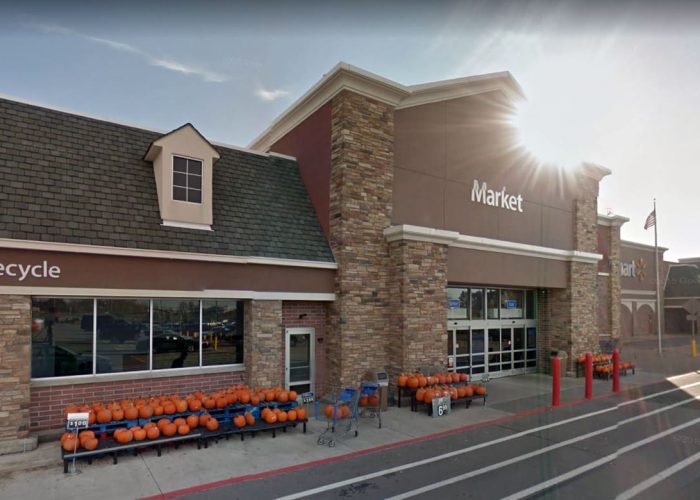 Exterior of a Walmart store with pumpkins displayed outside, showcasing fall seasonal produce.