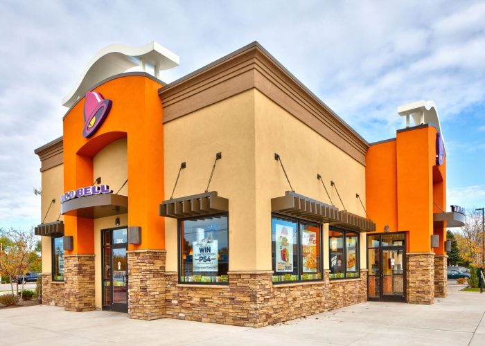 Taco Bell restaurant exterior with bright orange accents on a sunny day.