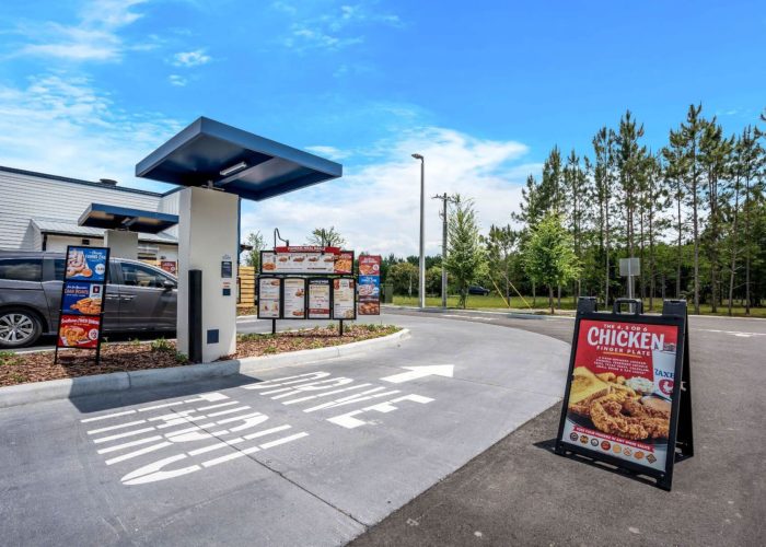 Drive-thru at fast food restaurant showcasing a chicken finger meal under a sunny sky. Enjoy quick service.
