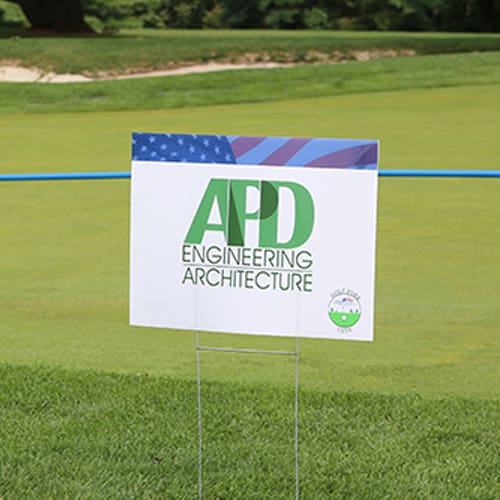 Sign on a golf course for APD Engineering Architecture, featuring an American flag theme.