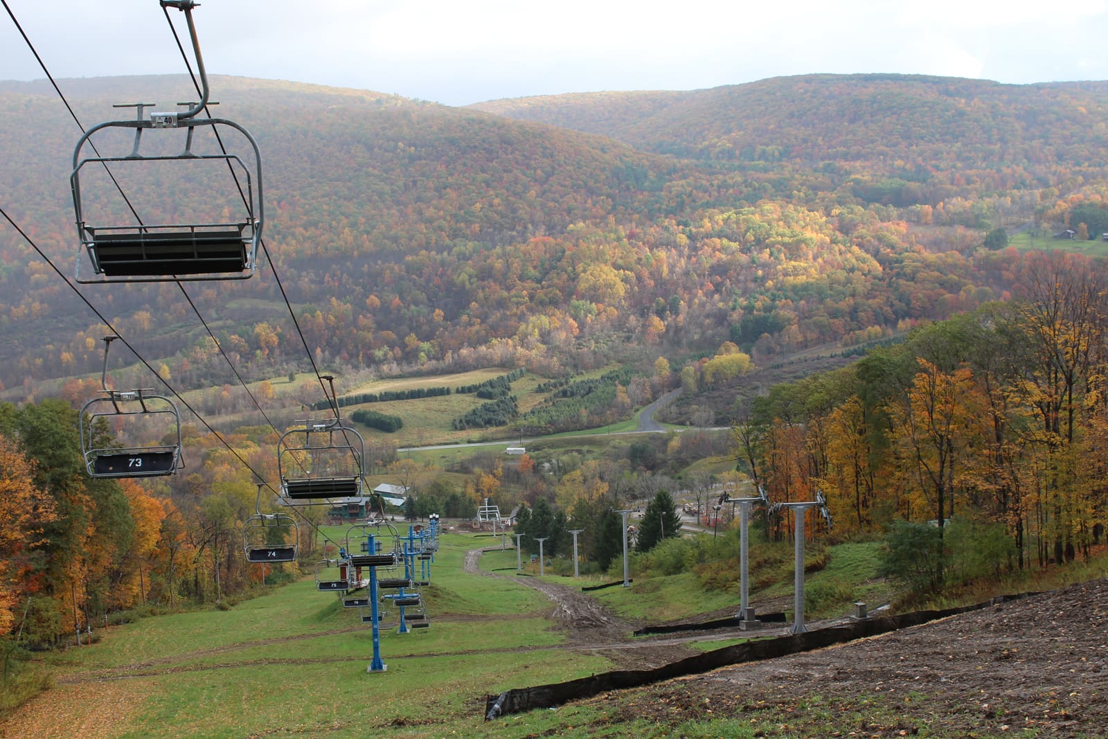 Fall foliage view from a ski lift at a scenic mountain resort, highlighting the vibrant autumn landscape.