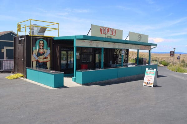 Trejo's Tacos stand on a sunny day with menu and vibrant artwork. Enjoy authentic street tacos here.