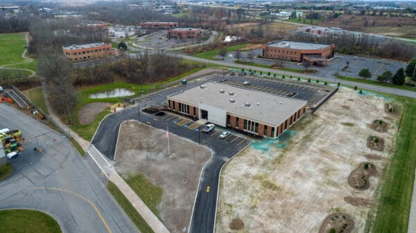 Aerial view of commercial building with parking lot surrounded by landscaping. Urban development concept.