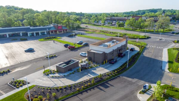 Aerial view of a drive-thru coffee shop with surrounding parking area in a shopping center.